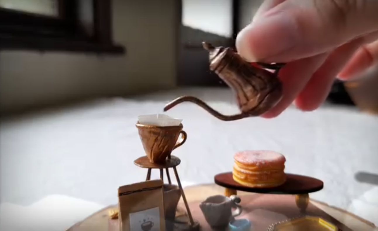 手指提起袖珍手沖壺，對著濾杯注水