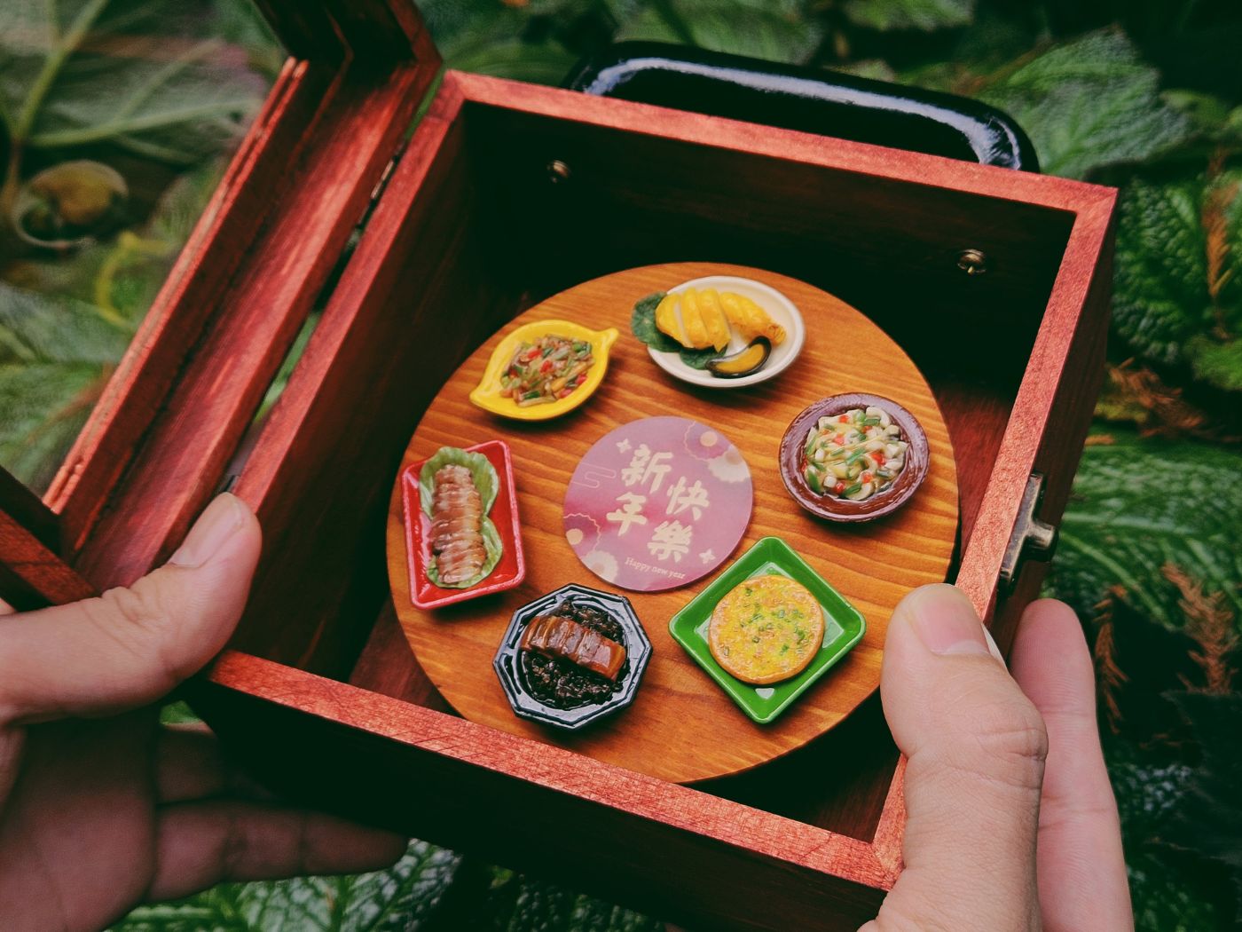 雙手捧著打開的袖珍年菜禮盒